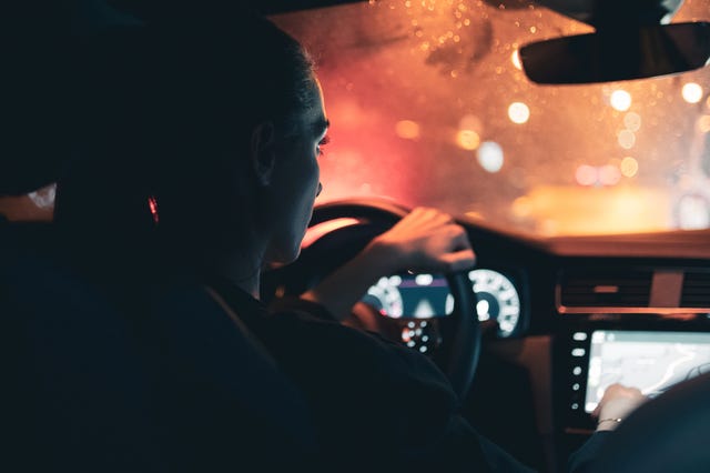 Vue arrière de la femme regardant la carte tout en conduisant une voiture