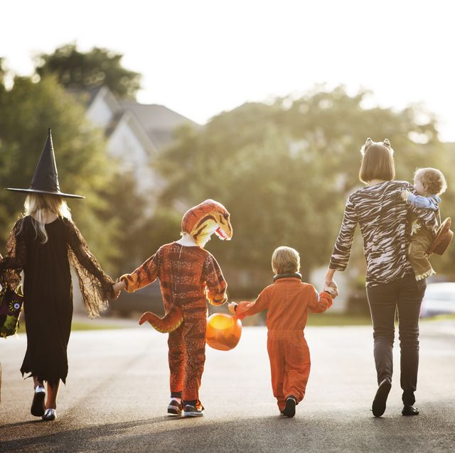 Rear view of women with children dressed for Halloween party walking on street