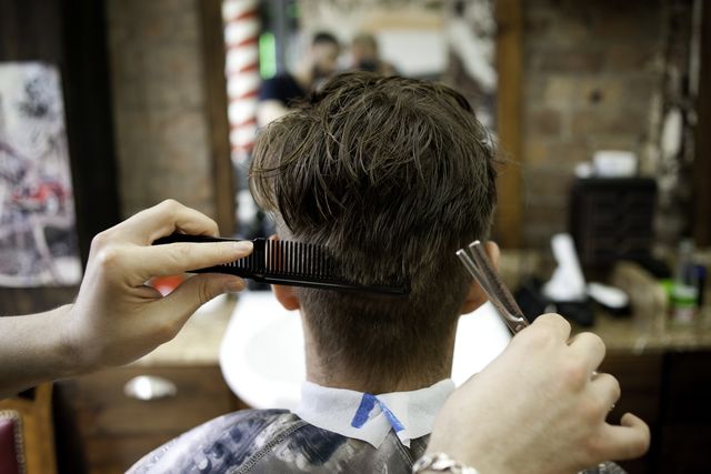 rear view of young man in barbershop having haircut