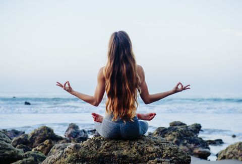 Mujer en pose de yoga frente al mar.