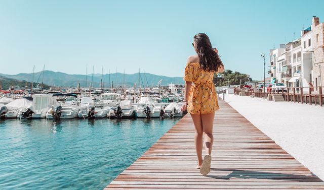 rear view young female walking on pier in catalonia,spain