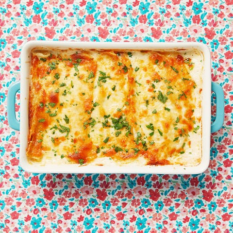 white chicken enchiladas in casserole dish on pink and blue floral background