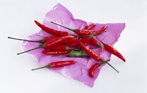 Red chilies and one green chili on paper, close-up