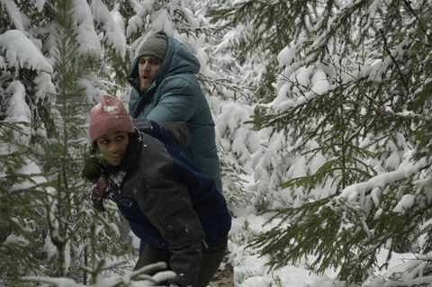 Hình ảnh một người đàn ông và một người phụ nữ đang tình cờ đi qua cảnh rừng đầy tuyết trong một bức ảnh tĩnh từ phim Netflix chấm đỏ