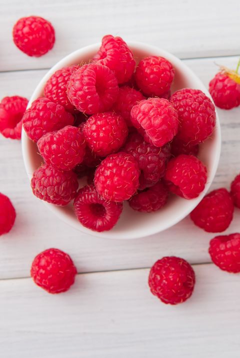 a bowl of red fresh raspberries on white rustic wood background, a good housekeeping pick for a healthy weight loss food