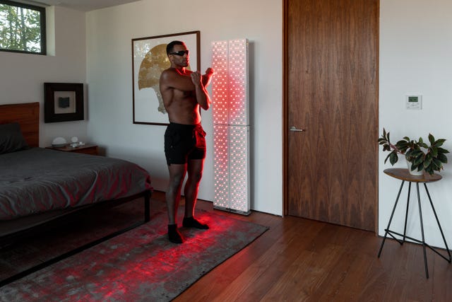 a man standing in a bedroom next to a red light wall