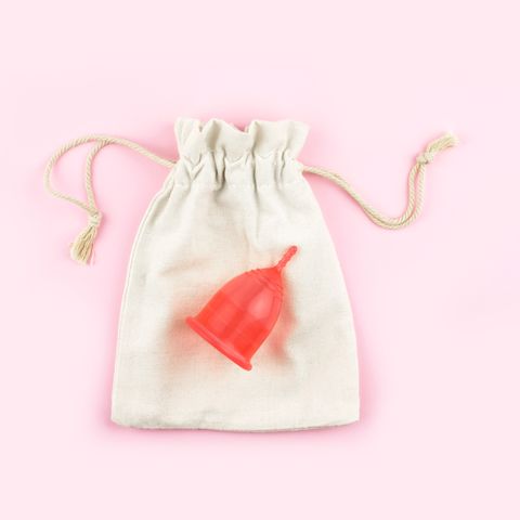 red menstrual cup on cotton bag on pink background