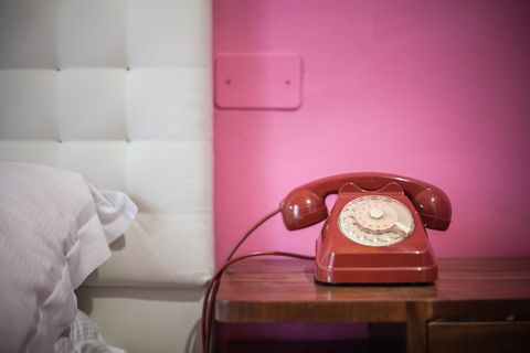 Red rotary telephone on bedside table
