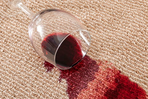 home mishap and domestic accident concept with close up of  a spilled glass of red wine on brown carpet