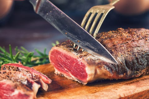 young women cutting medium roasted beef steak on the wooden board