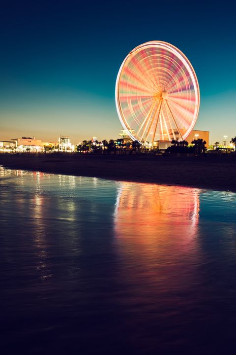 skywheel in motion reflected in ocean along the beach at night