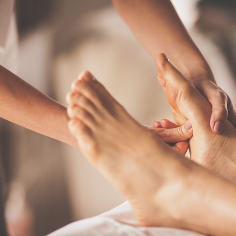 Reflexologist applying pressure to foot with thumbs