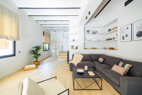 salón abierto moderno con sofá rinconera gris y estantería de obra