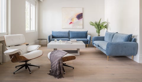 salón de diseño contemporáneo con dos sofás de terciopelo azul y una butaca con reposapiés en blanco