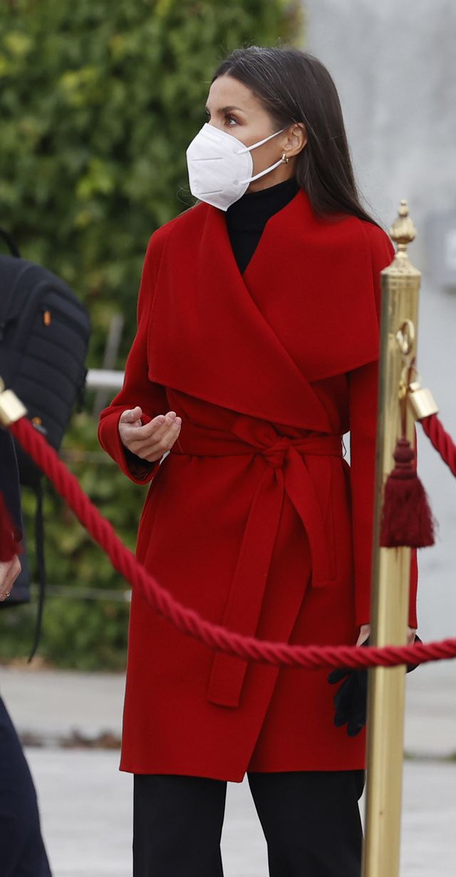 la reina letizia con el abrigo bata rojo de hugo bos, pantalones culotte negros y botas altas negras con tacón en la despedida antes de iniciar su viaje oficial a suecia