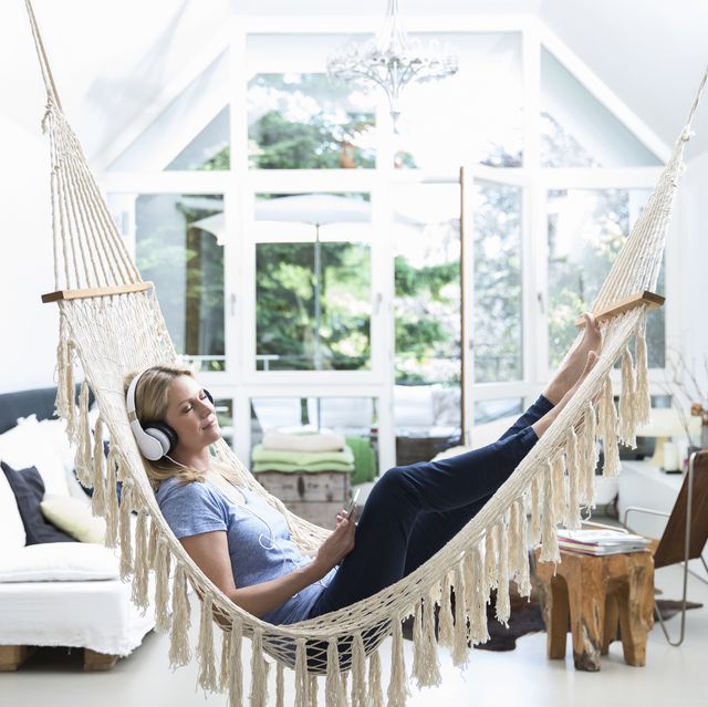 Relaxed woman at home lying in hammock listening to music
