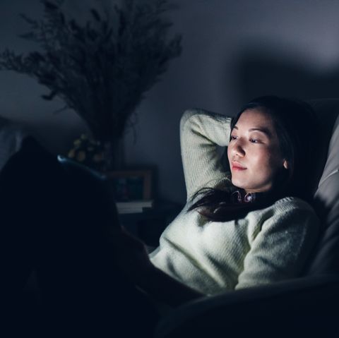 relaxed woman reading on digital tablet at night