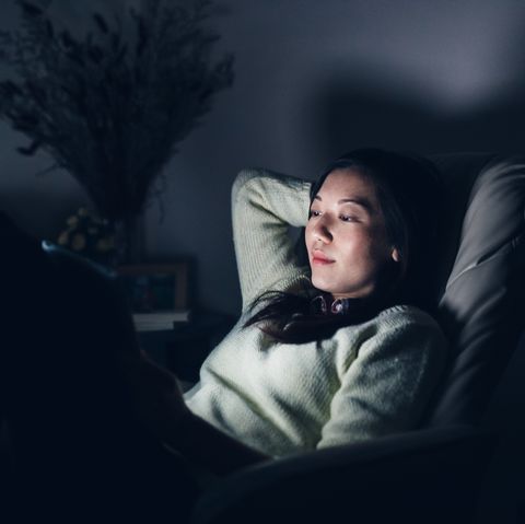 relaxed woman reading on digital tablet at night