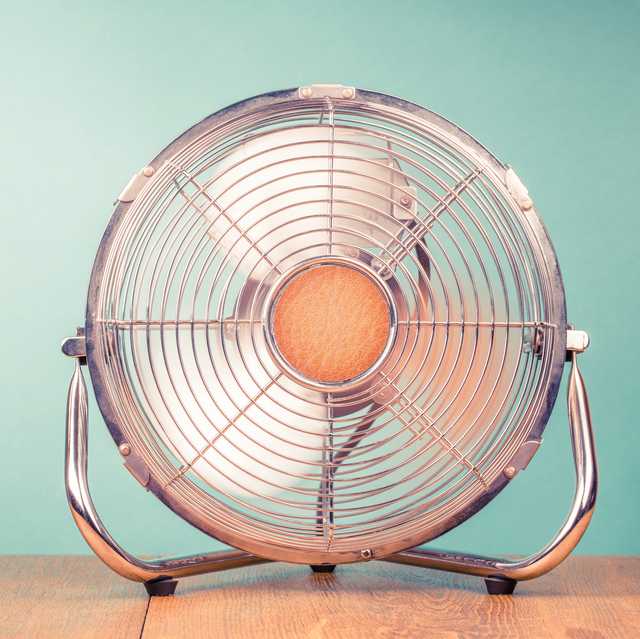 retro portable office or home cooling fan in working mode standing on table vintage instagram style filtered photo