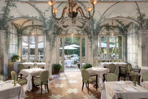 luxurious hotel restaurant with green chairs and green plant wallpaper