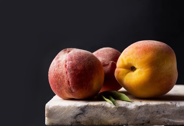 ripe peaches on a stone marble table dark background, low key creative art photo with fruits