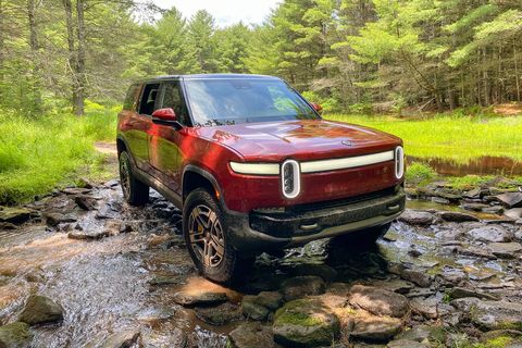 red rivian r1s parked in a rocky stream