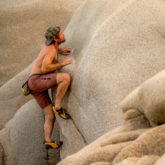 man climbing rock wall wearing roark shorks