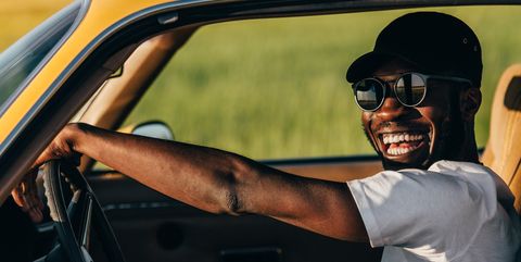 man in sunglasses and hat driving car