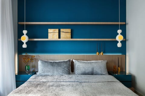 straight on photo of a large platform bed with two long open shelves above and with two pendant lights with yellow insets that look like egg yolks