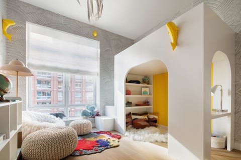 child's room with an arched area  with a fluffy white rug on the floor and several large poufs off to the left and small yellow decorative fish on the walls just under the ceiling line