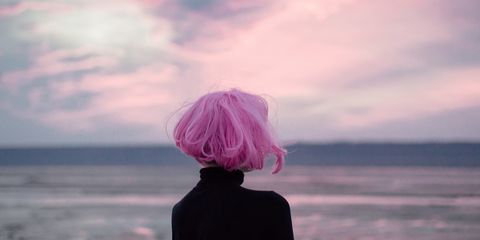 A woman wearing a pink wig looking into the sunset