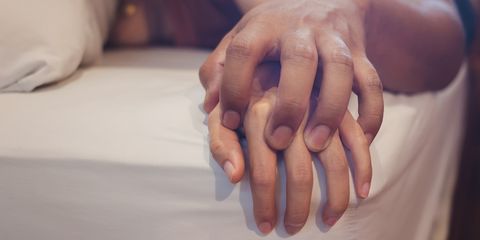 A couple lying hand in hand on a bed