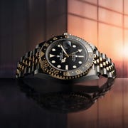 a rolex watch on a reflective table