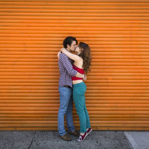 Romantic couple kissing in front of orange shutter