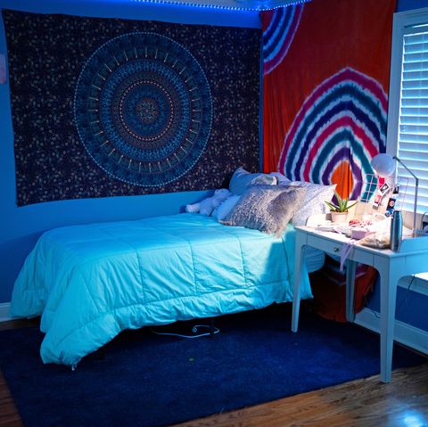 bedroom with tapestries, twinkly lights, and desk with photos