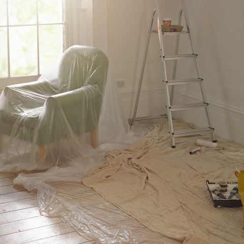 a room with dust sheets, a ladder and paint roller