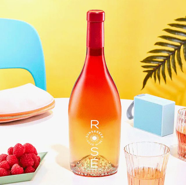 Sunseeker Rosé wine on a table surrounded by summer party essentials instant camera pineapple phone case speaker purse fruit glasses of wine