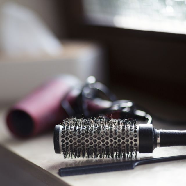 round hairbrush and hairdryer on a window ledge in a bathroom