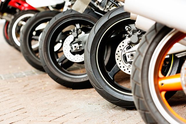 row of assorted motorbike wheels on brick surface