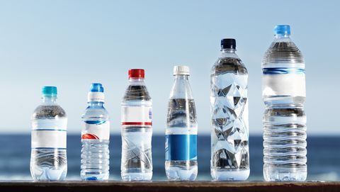 Row of assorted water bottles against the ocean