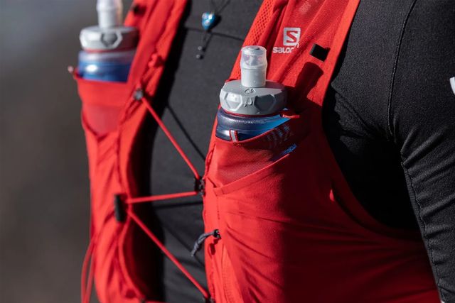 close up of a person wearing a hydration vest with water bottles