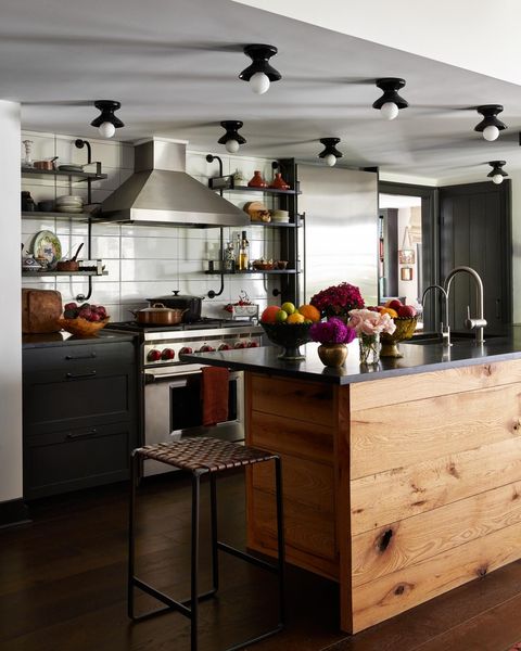 a kitchen with white backsplash black cabinets and an island