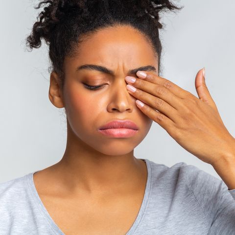 sad black girl touching her eye, suffering from conjuctivitis