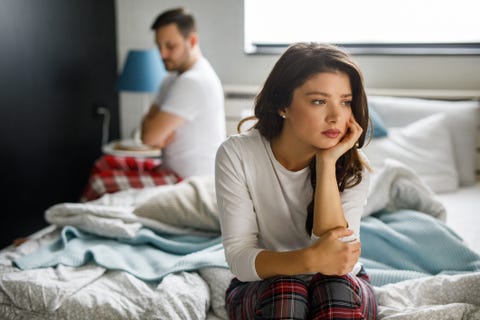 sad couple sitting on bed after having a quarrel