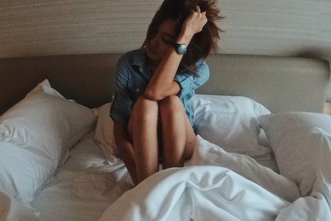 Sad Woman Sitting On Bed At Home