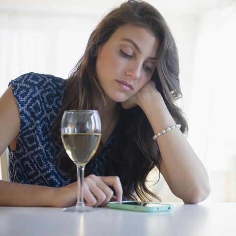sad woman with glass of wine texting