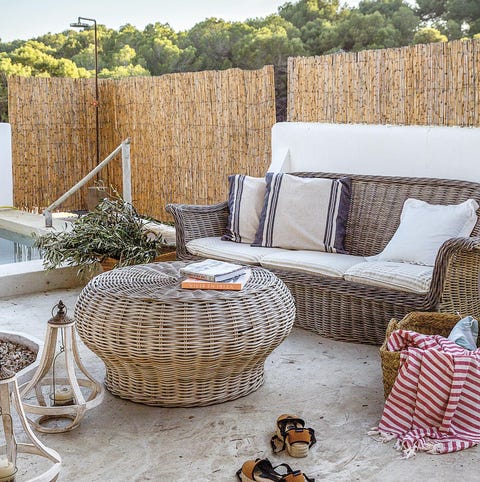 Salón exterior junto a las piscina con muebles de fibra