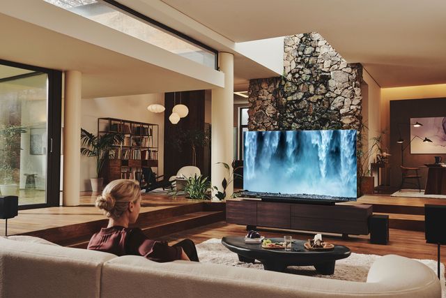 woman sitting on couch in living room watching samsung neo qled tv