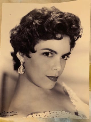 A portrait of the author's mother. She is wearing teardrop-shaped earrings and a lace dress. isabel gonzalez whitaker's mother sara at 18