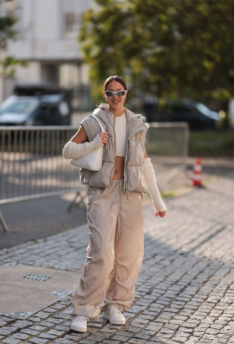 vrouw in beige outfit met parachute pants bodywarmer en armwarmers